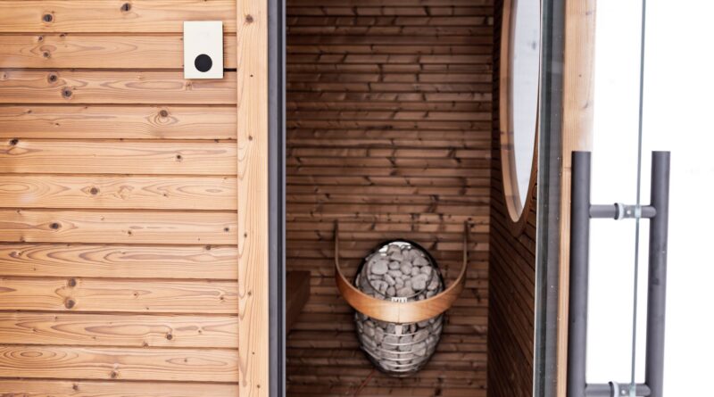 Compact two-person low-EMF infrared sauna in a cozy room with wood paneling and glass door.